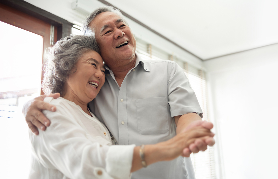 senior couple dancing in front of window