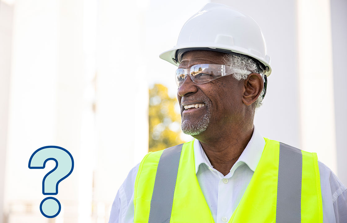 a senior man wearing safety glassses, a hard hat and a construction vest