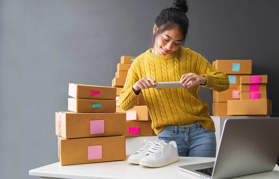woman taking a picture of shoes to sell online with boxes behind her
