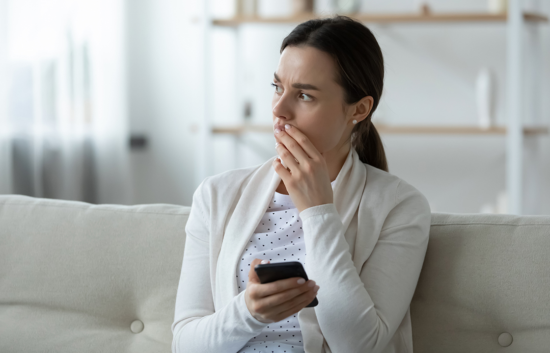 woman holding cell phone looking concerned